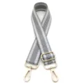 Nahaufnahme des grau-weißen Jacquard-Webmusters auf dem verstellbaren Taschenriemen - Goldene Schnalle / Grau