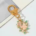 Détail d'un porte-clés doré avec fermoir coeur, rose rose et breloque papillon - Fleur de Papillon Branche Rose