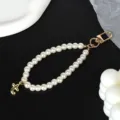 Macro view of elegant white pearl phone strap with golden lobster clasp and letter charm - Letter T(T)