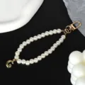 Detail of elegant white pearl keychain with gold initial G charm on black background - Letter G(G)