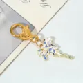 Close-up detail of a gold metal flower bouquet keychain with enamel floral pendant - Blue and White Iris