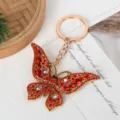Macro view of a gold-plated butterfly keychain encrusted with sparkling red rhinestones. - Red Diamond Butterfly