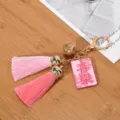 Gedetailleerd zicht op roze kwastjes sleutelhanger met gouden bel en geluksbedeltje - Vreugde (Lichtroze + Roze Kwast)