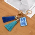 Detailed view of golden bell keychain featuring blue tassels and a Good Luck charm - Good Luck (Blue + Emerald Tassel)