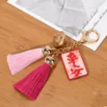 Close-up of tassel keychain with golden hollow palace bell and pink pendant - Peace (Light Pink + Fuchsia Tassel)