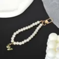Detail of white pearl phone strap with gold-plated letter M charm and lobster clasp - Letter W(W)