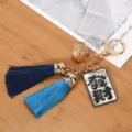 Close-up detail of a blue tassel keychain featuring a golden hollow bell and Rich tag - Fortune (Navy + Peacock Blue Tassel)