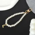 Close-up detail of white pearl phone chain with gold-plated metal clasp and letter J charm - Letter L(L)