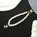 Close-up detail of a white pearl keychain strap featuring a gold-toned letter N charm - Letter N(N)