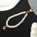 Detail view of elegant white pearl phone strap featuring a gold-tone letter J charm. - Letter J(J)