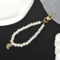 Detail view of pearl phone strap with gold-plated letter E charm and sturdy lobster clasp - Letter E(E)