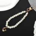 Detailed macro shot of white pearl phone lanyard featuring a gold-plated letter U charm - Letter U(U)