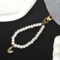 Detailed view of the white pearl chain with a gold-tone 'V' letter charm and metal clasp - Letter V(V)