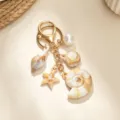 Close-up detail of a gold keychain featuring realistic shell conch and starfish charms. - Spiral Conch Seashell Keychain