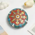 Detail view of a vintage ethnic style portable makeup mirror with colorful mandala pattern - Crimson Glaze