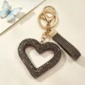 Detailed view of a sparkling hollow heart keychain with dark rhinestones and gold hardware. - Hollow Heart Rhinestone Keychain / Gunmetal