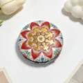 Close-up detail of vintage ethnic pattern on round foldable makeup mirror cover - Sandalwood Red Mandala
