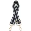 Detailansicht des schwarz-weißen Jacquard-Taschenriemens mit goldenen Metallhaken - Schwarz