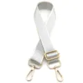 Detalle de correa de bolso tejida con patrón de espiga plateada y cierres dorados. - Plateado