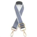 Detalle de correa ajustable para bolso con patrón de flechas azules y herrajes dorados. - Azul