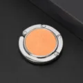 Close-up van de ronde opvouwbare tassenhaak met oranje glitters en zilveren frame. - Oranje (Glitter)