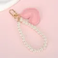 Détail du charm en forme de cœur rose et de la dragonne en perles nacrées synthétiques - Chaîne de Perles Blanches + Cœur Rose