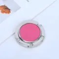 Nahaufnahme eines klappbaren runden Taschenhalters aus Metall mit pinkem Leder. - Vollkunstleder-Stil / Fuchsia