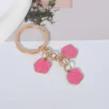 Close-up detail of a gold keychain featuring three beautiful pink enamel rose pendants - Rose Pink