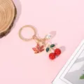 Detailed view of red cherry and maple leaf charms on a golden metal keychain. - Maple Leaf Cherry Flat Ring