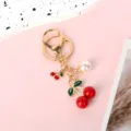 Detailed view of the red resin cherry and pearl charms on the golden keychain - Big And Small Cherry Lobster Buckle