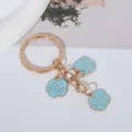 Detail of blue enamel rose charms on a gold-plated keychain with a polished finish. - Sapphire Blue