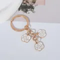 Detail shot of white enamel roses on a minimalist golden craft keychain pendant - White