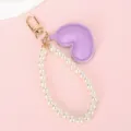 Detail van paarse kunstleren hart en parelketting voor telefoon met gouden sluiting - Witte Kralenketting + Paars Hart
