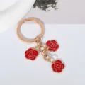 Elegant gold-tone keychain featuring three vibrant red enamel rose charms for gifts. - Red