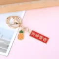 Detailed view of metal keychain with red enamel blessing tag and pineapple charm - Rectangle Smooth Success (Pear Charm)