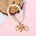 Close-up detail of pearl phone strap featuring elegant bow and crescent moon charms. - White Bow & Hollow Moon Style (Style 10)
