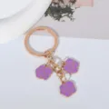 Detailed view of the purple enamel triple rose flower charms on the golden keychain - Purple