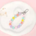 Detail van de telefoonarmband met macaronkleurige kralen en een witte hartjes hanger - Macaron Kralenketting + Wit Hart