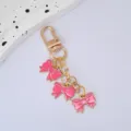 Close-up of a pink bow pendant keychain with gold-plated lobster clasp accessory. - Rose Red