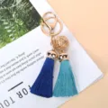 Detailed view of gold bell and vibrant blue silk tassels on a stylish gift keychain. - Dark Blue And Blue