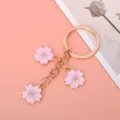 Close-up detail of three pink enamel cherry blossom charms on a gold-tone keychain - Pink