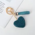 Detailweergave van een blauwe strass hart sleutelhanger met goudkleurige details. - Blauwe Diamant Stijl
