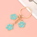 Close-up of three turquoise cherry blossom pendants on a golden metal keychain - Sky Blue