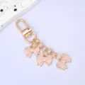 Detailed view of three pink enamel bow charms on a gold-plated lobster clasp keychain - Lotus Pink