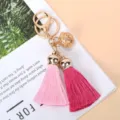 Détail d'un porte-clés à la mode avec deux glands et une cloche dorée évidée. - Rose Rouge + Rose