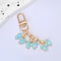 Detailed view of three light blue enamel bow pendants on a gold-colored metal keychain - Sky Blue