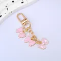 Detailed view of a gold-tone keychain featuring three adorable pink enamel bows - Pink