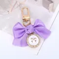 Detail van een paarse strik-sleutelhanger met een hanger van parels. - Paars