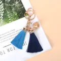 Detailed macro shot of golden bell and dual blue tassels keychain on a magazine. - Navy Blue
