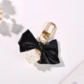 Close-up view of black ribbon bow keychain with an elegant pearl cube charm detail - Black